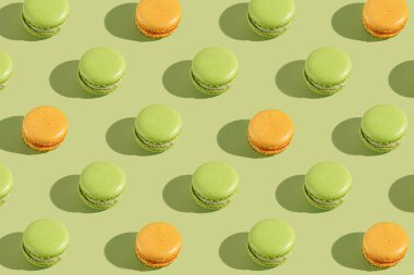 Yeşil ve turuncu bir kurabiyenin sert ışık deseni açık yeşil kağıt arka planda fotoğraflanmış.