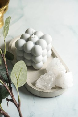 Beton tepside gri-mavi baloncuk mumu ve pastel mavi arka planda beyaz kristaller.