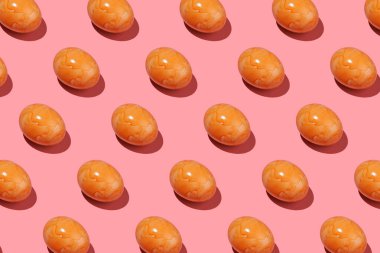 Pembe arka planda turuncu renkli bir Paskalya yumurtasının sert ışık deseni