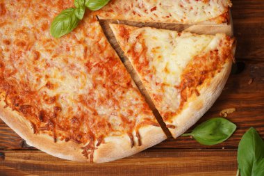 Küçük kaselerdeki pizza ve pizza malzemelerinin yarısının üstü: mozzarella peyniri küpleri, kiraz domatesleri, ahşap masadaki taze fesleğen yaprakları.