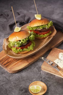 Vejetaryen köfteli iki hamburger, marul, domates ve tahtanın üzerinde bir dilim limon.