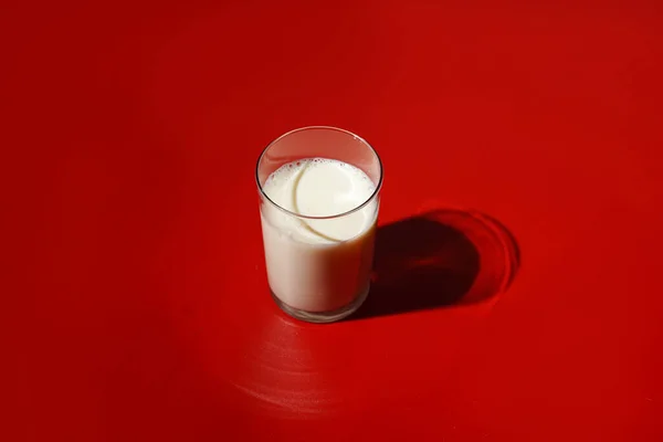 強い光の影を持つ明るい赤い表面のミルクのガラスは — ストック写真