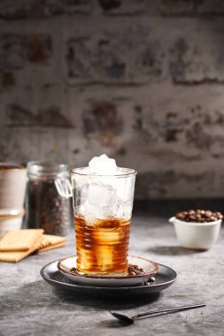 Kahverengi sıvı kahveyle doldurulmuş buzlu bir bardak.