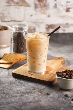 Tahtada buz küpleri ve sütlü kahve olan bir bardak.
