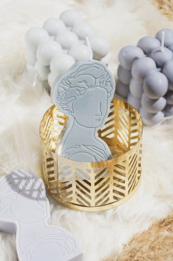 Altın bir kalıpta Yunan tanrıçası şeklinde gri bir mum.