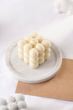 Beyaz masa örtüsü üzerinde beyaz bir mum, yakın plan.