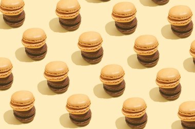 İki kremalı ve çikolatalı makarna üst üste istiflenmiş - bej renkli yüzeyde sert ışık deseni