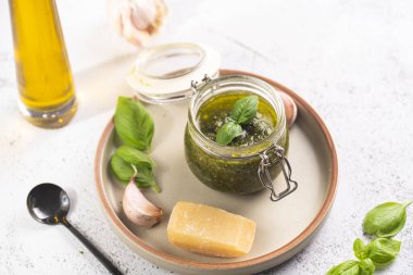 Sert peynirli pekorino, sarımsak karanfili ve taze fesleğen yapraklı yeşil İtalyan fesleğen soslu küçük bir mason kavanozu.