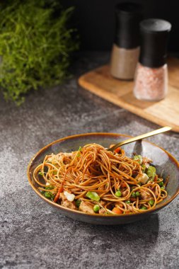 Tavuklu İtalyan makarna, yeşil fasulye, peynirli mozzarella ve yeşil kasede kekik gri beton yüzeyde tahta tahtada.