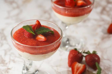 Geleneksel kremalı tatlı panna cotta ile birkaç bardak naneli ve çilekli reçelli mermer yüzeyde taze çilek