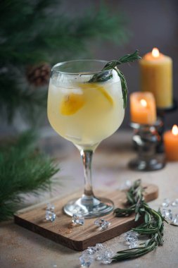 Noel arifeli büyük bir bardak biberiyeli limonata ve Noel süslemeleri, ışıklar ve mumlarla çevrili limonlar.