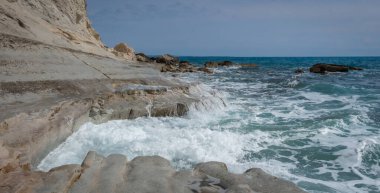 Kıbrıs Rum Kesimi 'ndeki kayalık Zapalo Sahili' nin manzarası. Deniz dalgaları sahile vuruyor, sıçramalar ve ferahlatıcı bir kıyı atmosferi yaratıyor.