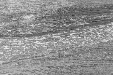 Kıbrıs kıyılarında siyah beyaz yumuşak köpüklü sakin deniz dalgaları sakin ve minimalist bir deniz manzarası yaratıyor.