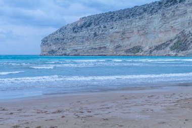 Akşamları huzurlu Kıbrıs plajı kayalık kayalıklar, yumuşak sahil şeridi ve alacakaranlıkta sakin bir kum.