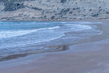 Akşamları huzurlu Kıbrıs plajı kayalık kayalıklar, yumuşak sahil şeridi ve alacakaranlıkta sakin bir kum.
