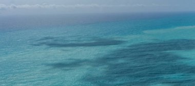 Kıbrıs 'ta sakin Akdeniz, hafif dalgalanmalar ve çeşitli mavi renkler gösteriyor, yumuşak ve sakin bir deniz manzarası yaratıyor