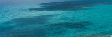 Kıbrıs 'ta sakin Akdeniz, hafif dalgalanmalar ve çeşitli mavi renkler gösteriyor, yumuşak ve sakin bir deniz manzarası yaratıyor