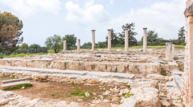 Kıbrıs 'taki Apollo Hylates Sığınağı' nın antik kalıntıları, yıpranmış taş yapılar ve parlak Akdeniz ışığı altında ayakta duran sütunlar yer alıyor.