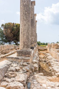 Kıbrıs 'taki Apollo Hylates Sığınağı' nın antik kalıntıları, yıpranmış taş yapılar ve parlak Akdeniz ışığı altında ayakta duran sütunlar yer alıyor.