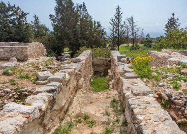 Kıbrıs 'taki Apollo Hylates Sığınağı' nın antik kalıntıları, yıpranmış taş yapılar ve parlak Akdeniz ışığı altında ayakta duran sütunlar yer alıyor.