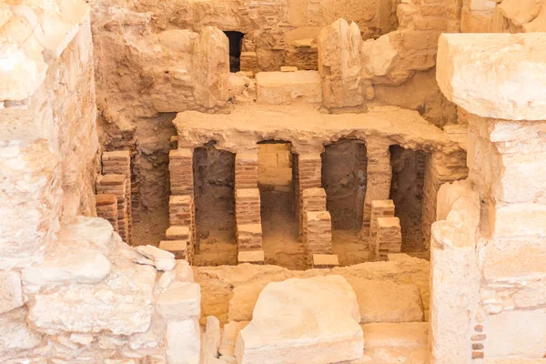 Kıbrıs 'taki Apollo Hylates Sığınağı' ndaki antik banyo kalıntıları, doğal ışık altında eskimiş taş kalıntıları ve tarihi mozaik parçalarının yer aldığı antik bir yapı.