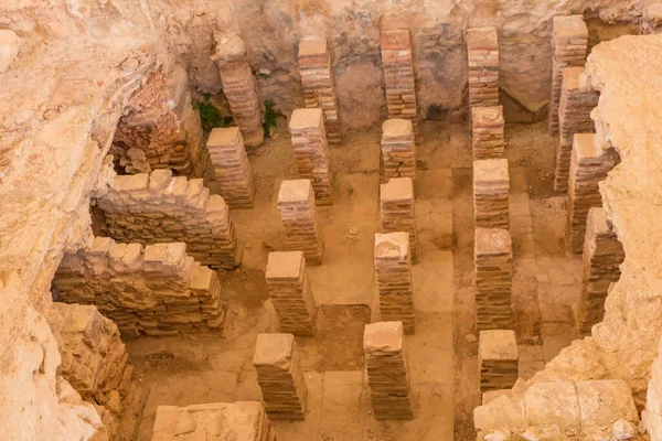 Kıbrıs 'taki Apollo Hylates Sığınağı' ndaki antik banyo kalıntıları, doğal ışık altında eskimiş taş kalıntıları ve tarihi mozaik parçalarının yer aldığı antik bir yapı.