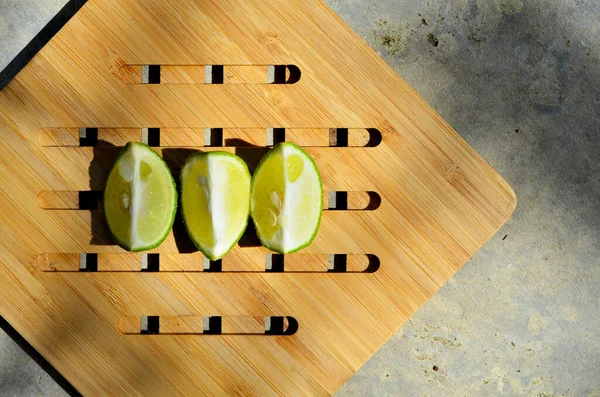 three slices of limes (Citrus aurantiifolia) on a wooden tray. commonly used in tropical restaurants with hot weather good for detoxification. Top left view with selective focus