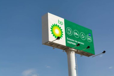 Papaz, İspanya; 23 Eylül 2021: Mavi gökyüzüne karşı bir alışveriş merkezinde logo ve hizmet sunan büyük bir BP işareti. BP eski adıyla British Petroleum, öncelikle petrol ve doğalgazla uğraşan bir enerji şirketidir..