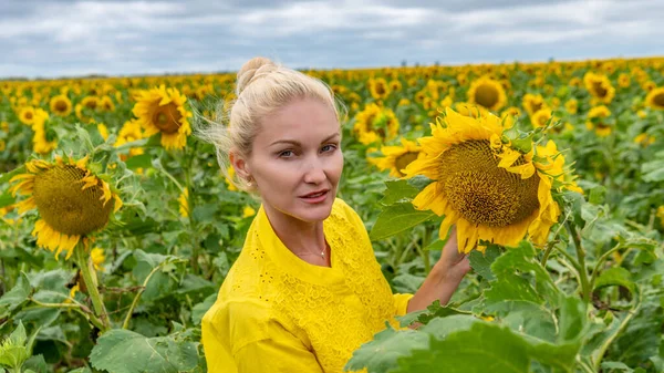 Donna gioiosa in un abito giallo adulto con un tipo sguardo nuvole blu giorno ed estate — Foto Stock