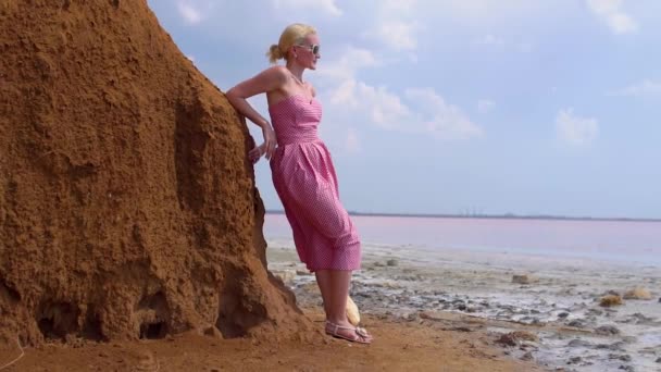 Joyeux jeune femme en robe rouge sur le fond d'un lac rose avec un ciel bleu un jour d'été — Video