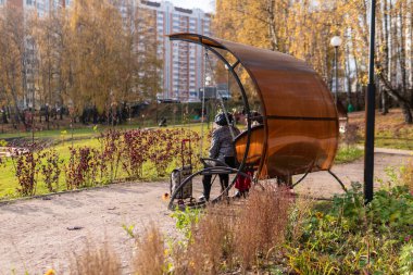 Parktaki vazo, yeşil çimlerin içindeki metal bir çöp tenekesi taşların yakınındaki yolda, öğleden sonra güneşli havada konseptin tadını çıkar. Bahçe salıncakları.
