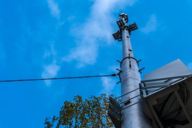 Hücre kulesi mavi gökyüzüne karşı kablosuz bulutlar ve kabloyla ağaçlar