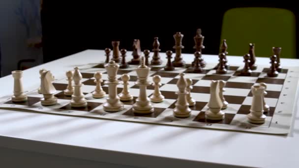 Zahrajte si krásné stromové šachy na čtvercovém stole v hnědé šachovnici, figurky jsou černé a věže, královny a králové, koně stůl ve tmě, stylový pro reklamní design. — Stock video