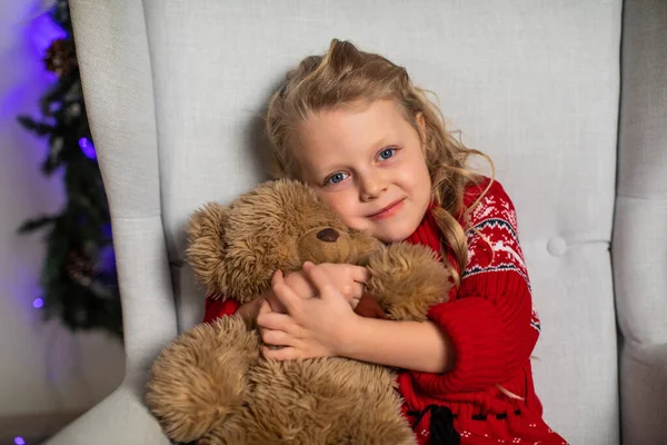 Girl hugs Teddy bear in red sweater for Christmas