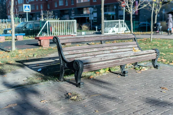 Um banco à sombra de uma madeira no parque no fundo do carro em estilo de pedra — Fotografia de Stock