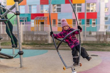 Oyun parkı, dönen bir pipoyla oynayan bir çocuk, eğlence merkezinde kalın bir ceket ve şapka takan bir kız, neşeli..