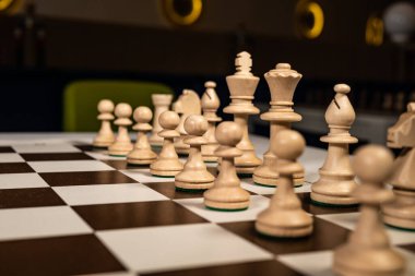 Kahverengi bir kafeste kare bir masada tahta satranç oynayın. Piyonlar ve kaleler, vezirler ve krallar. Karanlıkta atlar masası..