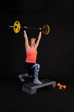 Halterli halterli bir platformda spor yapmak. Siyah bir arka planda güzel gözlerle spor yapmaya gidin.