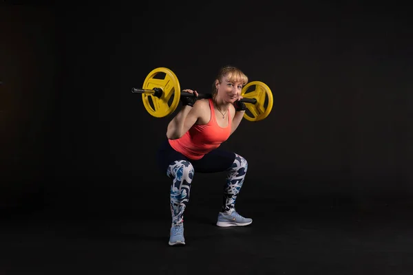 Fitness em uma plataforma de passo com um sino de barra com halteres. Entre para esportes em um fundo preto com lábios suaves — Fotografia de Stock