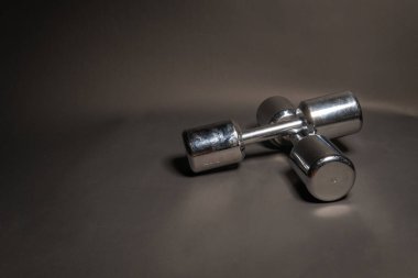 Fitness dambılları uzanır, siyah arka planda metalik bir renkle parlar.