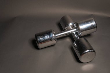 Atletizm dambılları yalan söyler, siyah arka planda ayna renginde parlar.