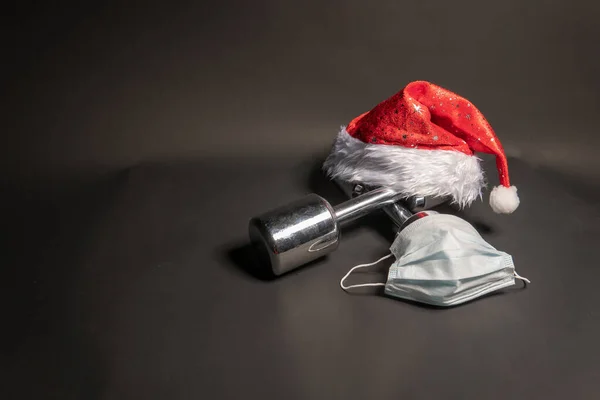 Hantle do fitnessu Santa Claus na czarnym tle z maską medyczną covid19 — Zdjęcie stockowe