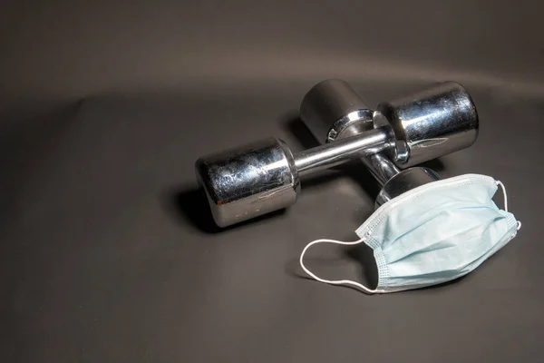 Fitness halters liggen met medisch masker van covid19, op een zwarte achtergrond — Stockfoto