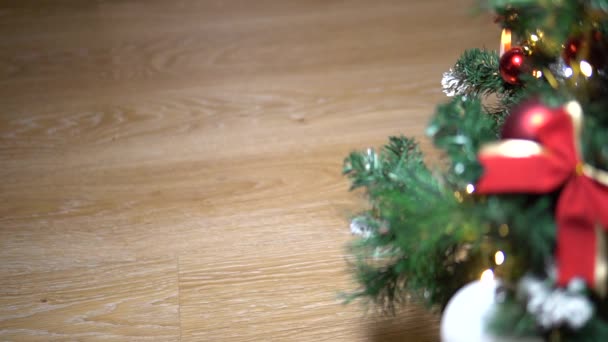 Der Weihnachtsmann geht in Stiefeln auf den Boden neben dem Weihnachtsbaum. Rote Schleife ist wie der Weihnachtsmann — Stockvideo