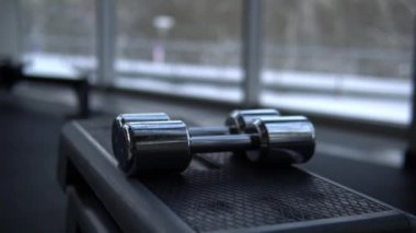 Spor salonundaki dambıllar adamı kaldırır. Bir spor kulübünde el ele tutuşmak kış öğleden sonrası penceresinin önünde kasları titretiyor.