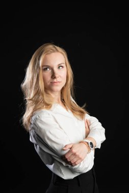 Siyah bir arka planda beyaz bir bluzla duruyor. Neşeli, karşılaştırma konsepti, stüdyoda, iş kadını, sarışın