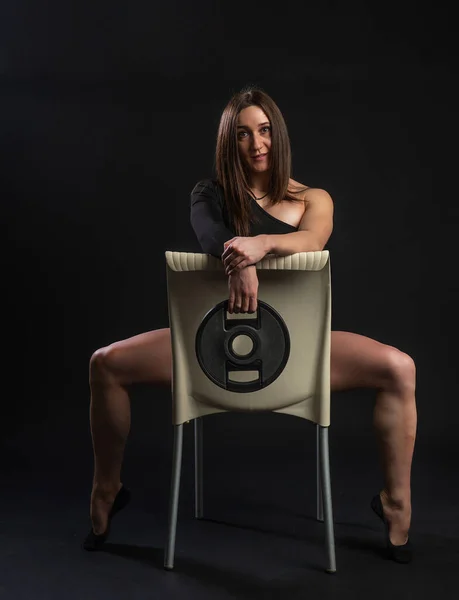 Fitness woman gym black. In a black bathing suit. sports, diet. Butt shape, torso Waist belly. sits on a chair — Stock fotografie