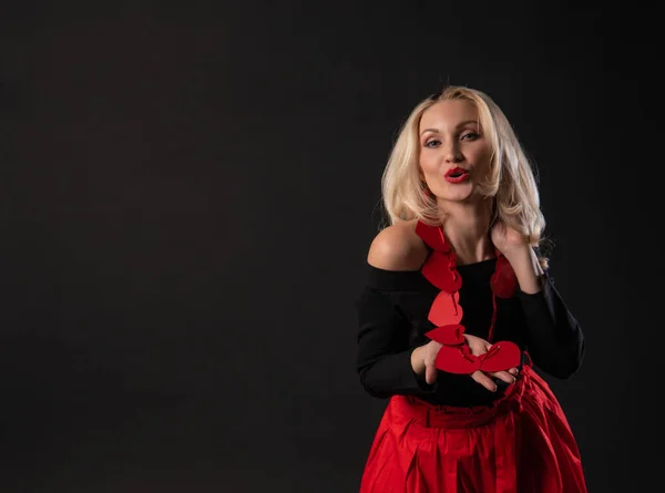 Una ragazza tiene una ghirlanda di cuore San Valentino rosso, felicità, sul pavimento cuori matrimonio. la forma della luna di miele. emozione per sempre, cornice in un abito rosso ragazza, a piedi nudi — Foto Stock