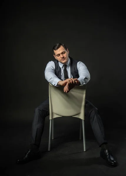 Üç parçalı takım elbise içinde bir sandalyede genç adam üç parçalı takım elbise iş adamı akıllı, sıradan bir portre. Satış elemanı memnuniyeti, başarı yalnızlık geçmişi siyah vücut geliştirici