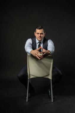 Sandalyede üç parçalı bir takım elbise içinde genç adam üç parçalı takım elbiseli yetişkin adam, genç adam mutlu. Güzel şehir, modaya uygun havalı arka plan Siyah vücut geliştirici